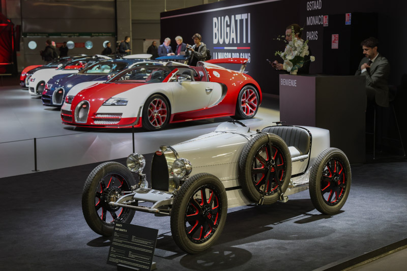 Bugatti 35 Baby II vor einer Reihe von Bugatti Veyron - Ultimate Supercar Garage an der Rétromobile Paris 2026 (© Bruno von Rotz)